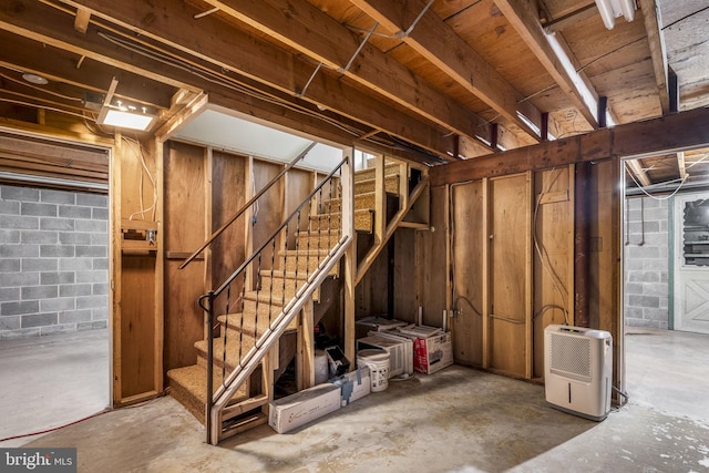 unfinished below grade area featuring concrete block wall and stairs