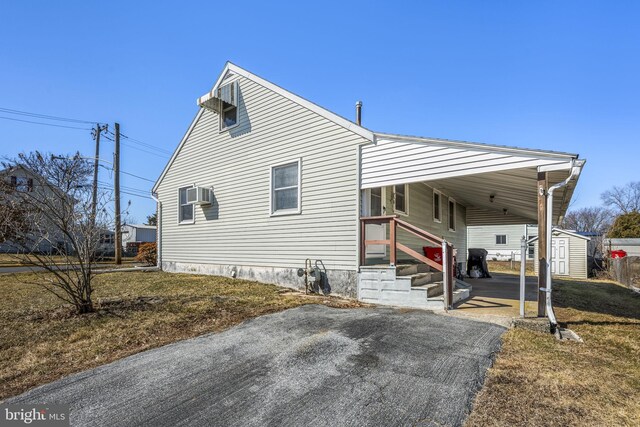 view of front of property featuring aphalt driveway, an attached carport, and a wall mounted air conditioner