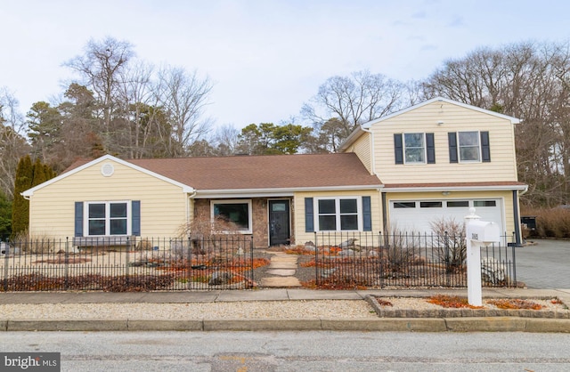 traditional-style house featuring a fenced front yard, driveway, a shingled roof, and an attached garage