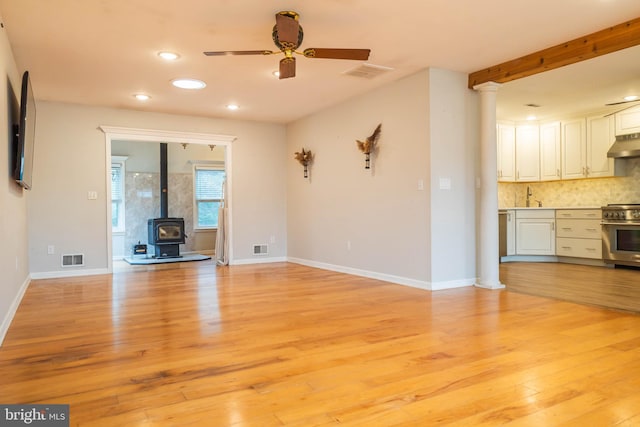 365 Heritage Way, Tuckerton, NJ 08087 - unfurnished living room featuring a wood stove, light wood-style flooring, a sink, and visible vents