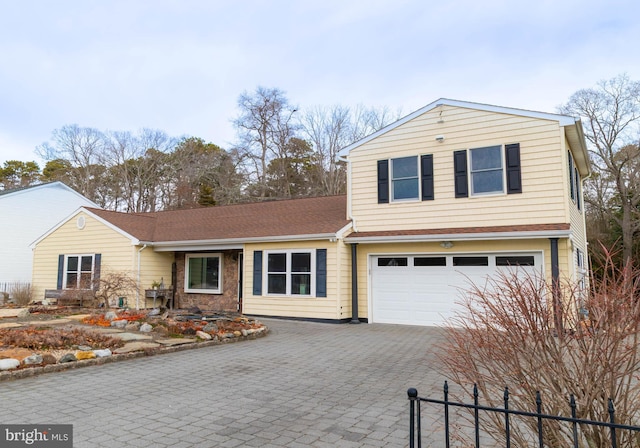 traditional-style home featuring an attached garage, stone siding, decorative driveway, and roof with shingles