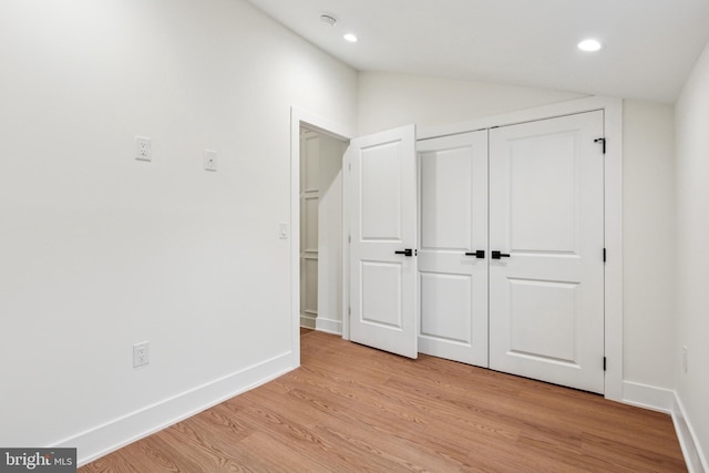 unfurnished bedroom featuring light wood finished floors, baseboards, vaulted ceiling, a closet, and recessed lighting