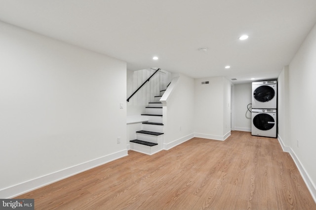 finished below grade area with stacked washer and dryer, recessed lighting, light wood-style floors, and baseboards