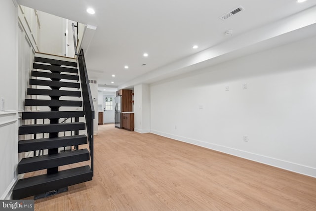 unfurnished living room featuring recessed lighting, visible vents, baseboards, stairway, and light wood-type flooring