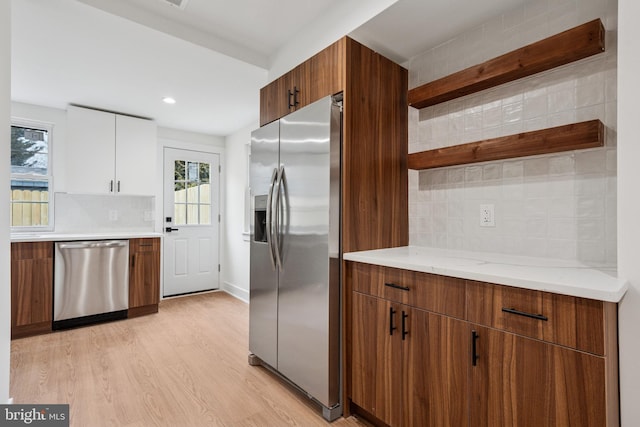 kitchen with stainless steel appliances, a healthy amount of sunlight, backsplash, open shelves, and light wood finished floors