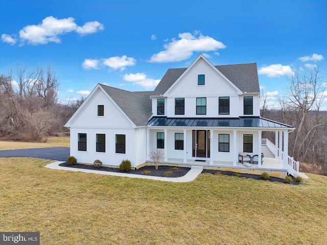 modern inspired farmhouse featuring a front yard, a standing seam roof, covered porch, and roof with shingles