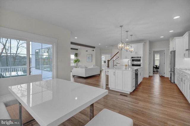 kitchen with light wood-type flooring, plenty of natural light, white cabinetry, and stainless steel appliances