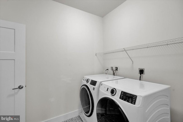 washroom with laundry area, washing machine and clothes dryer, and baseboards