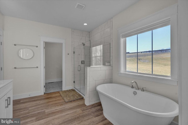 full bathroom featuring a freestanding tub, wood finished floors, vanity, baseboards, and a stall shower