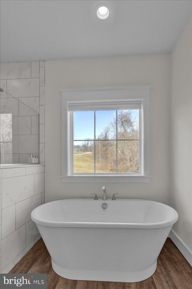 full bath featuring a freestanding tub and wood finished floors