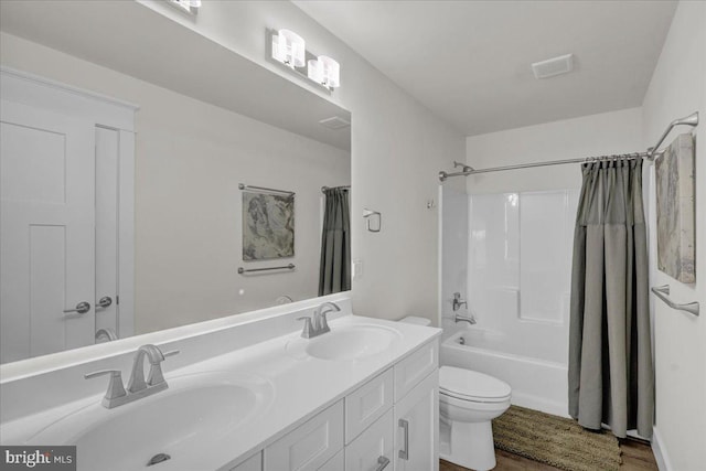 bathroom with double vanity, shower / bath combo with shower curtain, a sink, and toilet