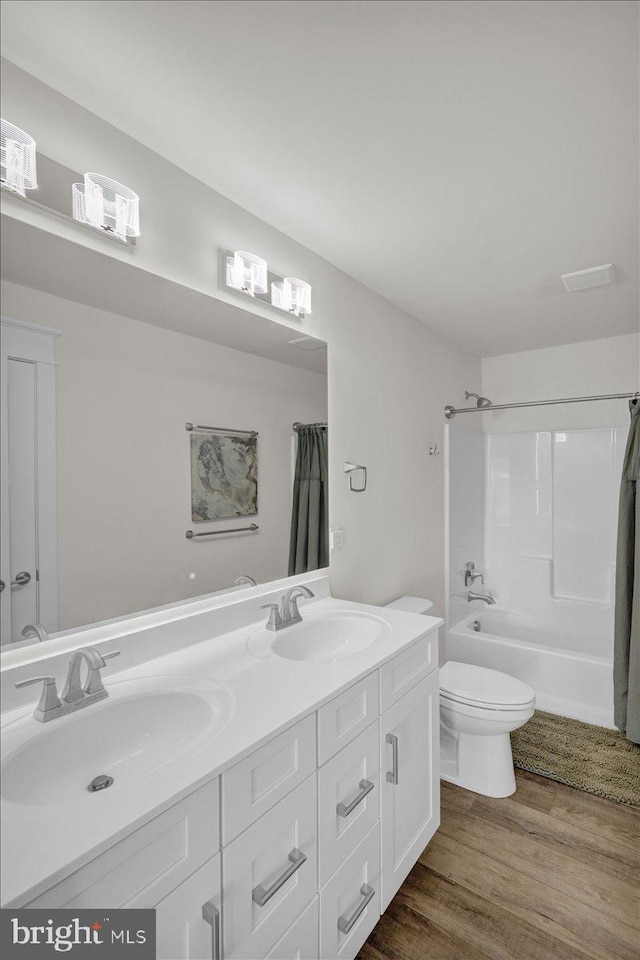 full bath featuring wood finished floors, shower / bath combo with shower curtain, a sink, and toilet