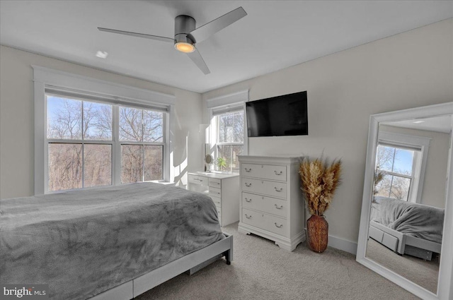 bedroom with ceiling fan, baseboards, and light colored carpet