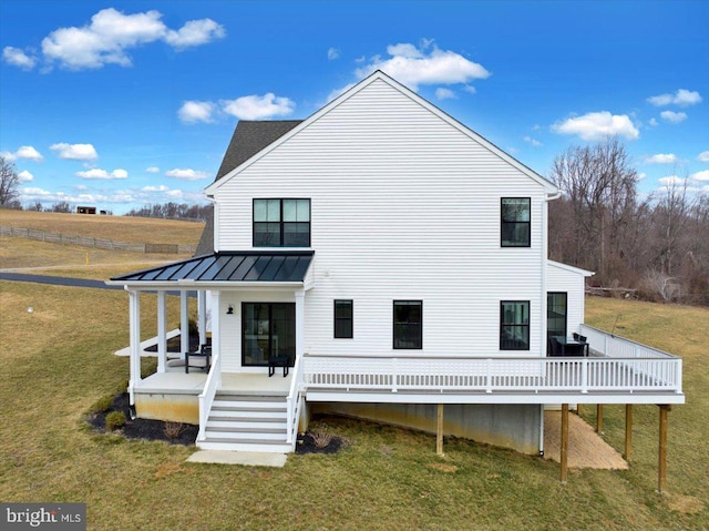 rear view of house featuring a standing seam roof, a lawn, and metal roof