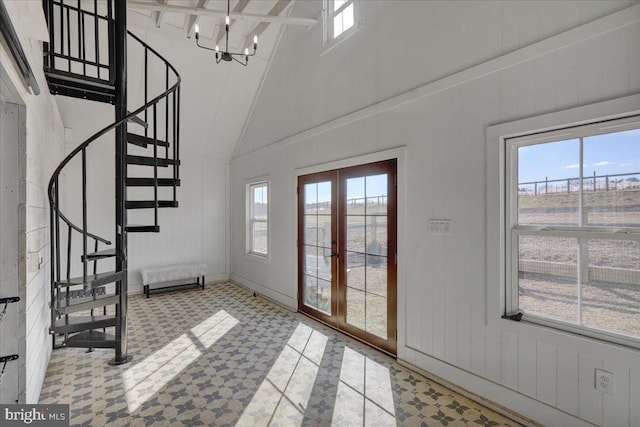 entrance foyer with high vaulted ceiling, a wealth of natural light, french doors, and stairs