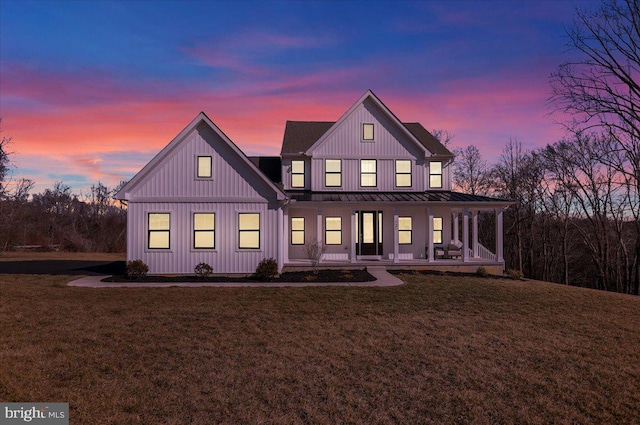 rear view of property featuring metal roof, covered porch, a yard, board and batten siding, and a standing seam roof