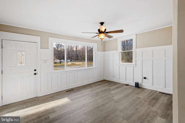 spare room featuring visible vents, wood finished floors, ceiling fan, and wainscoting