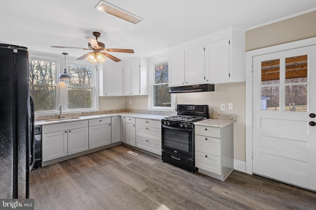 kitchen with black appliances, wood finished floors, a ceiling fan, and a sink