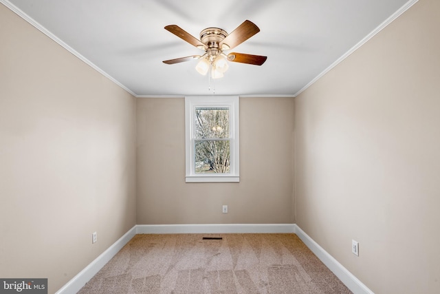 carpeted spare room with ornamental molding, visible vents, baseboards, and ceiling fan