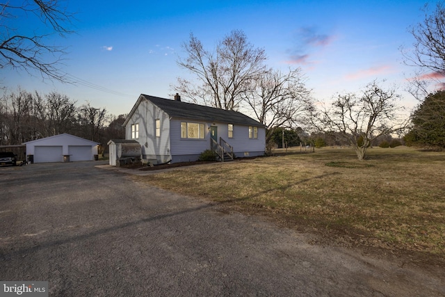 view of front of house featuring a detached garage, entry steps, a front yard, a chimney, and an outbuilding