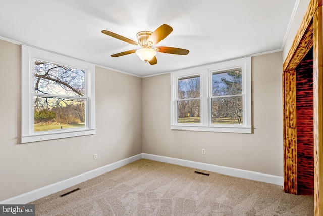 carpeted empty room with visible vents, ceiling fan, and baseboards