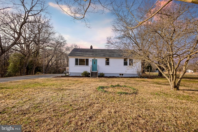 ranch-style home featuring driveway, a chimney, a front yard, and entry steps