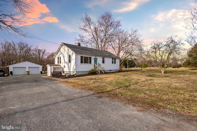 view of front of home with a front lawn, entry steps, an outdoor structure, a garage, and a chimney