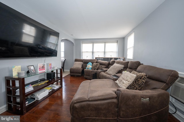 living area featuring arched walkways, baseboards, and wood finished floors