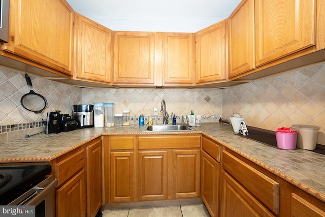 kitchen featuring light tile patterned floors, a sink, light countertops, stainless steel range with electric cooktop, and backsplash