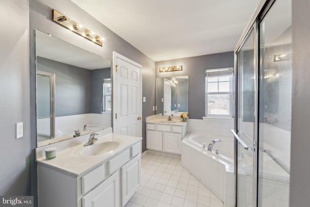 bathroom featuring a sink, a garden tub, two vanities, and tile patterned floors