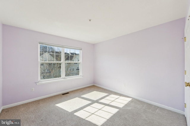 spare room with carpet flooring, visible vents, and baseboards