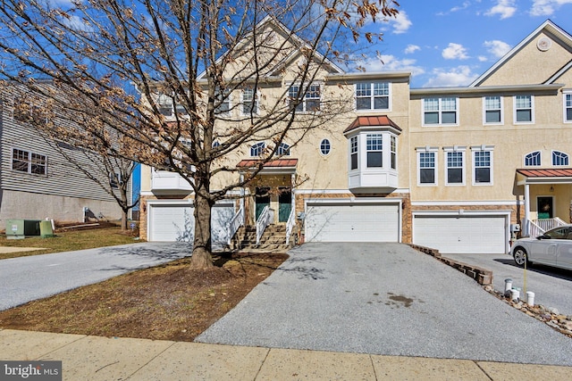 view of property with driveway, central AC, stucco siding, a garage, and brick siding