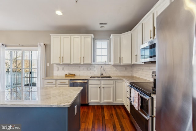 kitchen featuring dark wood-type flooring, backsplash, appliances with stainless steel finishes, and a sink