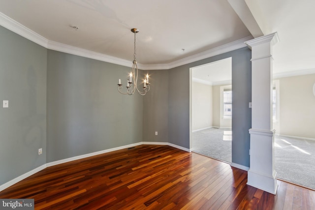 spare room featuring hardwood / wood-style flooring, an inviting chandelier, crown molding, baseboards, and ornate columns