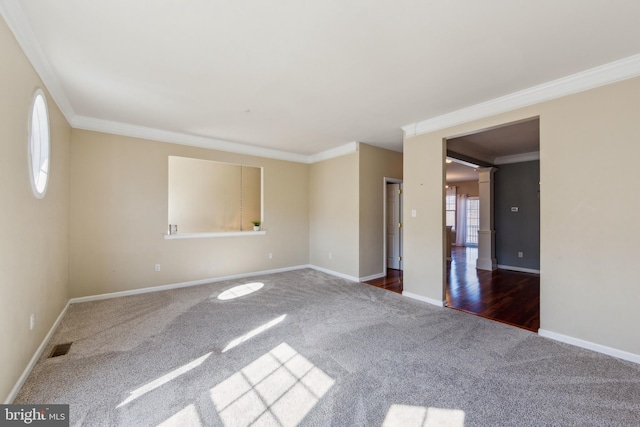 carpeted empty room featuring crown molding, baseboards, and ornate columns