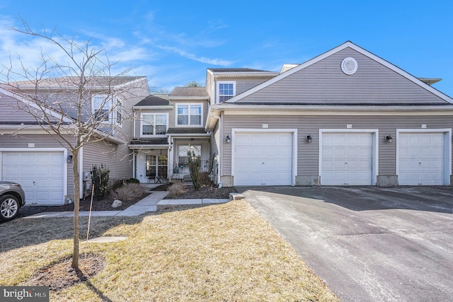 view of property with covered porch, a garage, and driveway