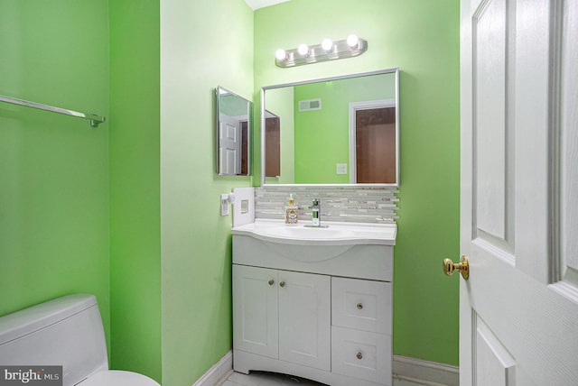 half bath featuring vanity, visible vents, baseboards, decorative backsplash, and toilet