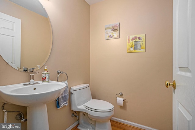 bathroom featuring baseboards, toilet, and wood finished floors