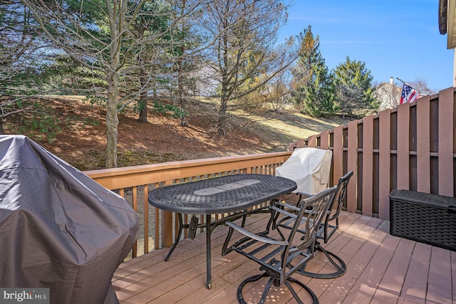 wooden terrace with outdoor dining area and a grill