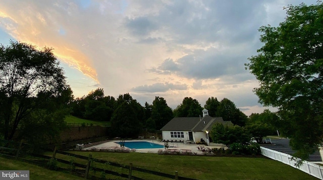 pool at dusk with a patio, a fenced in pool, a fenced backyard, and a lawn