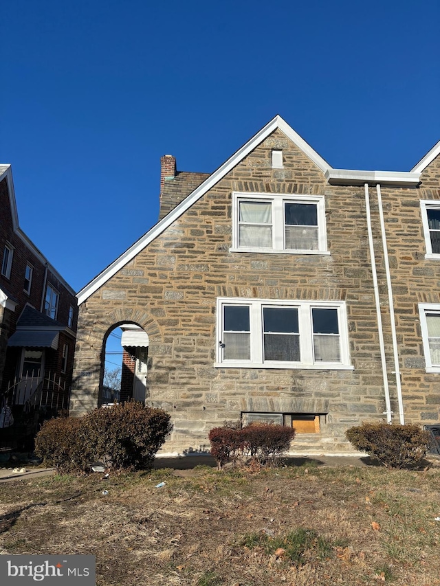 view of home's exterior with stone siding and a chimney