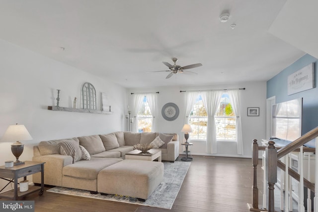 living area featuring stairs, dark wood-type flooring, a ceiling fan, and baseboards