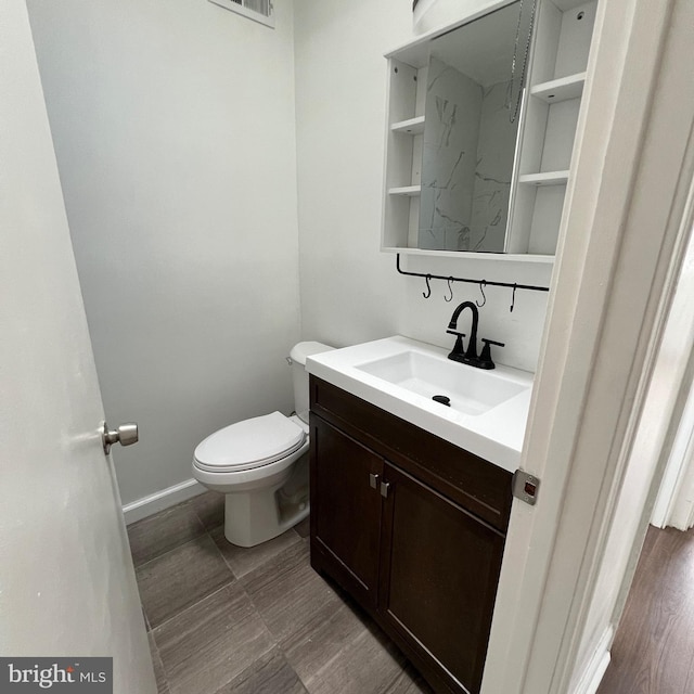 bathroom featuring toilet, baseboards, and vanity