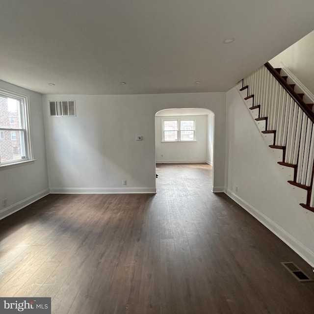 unfurnished living room featuring stairs, visible vents, and dark wood-style flooring