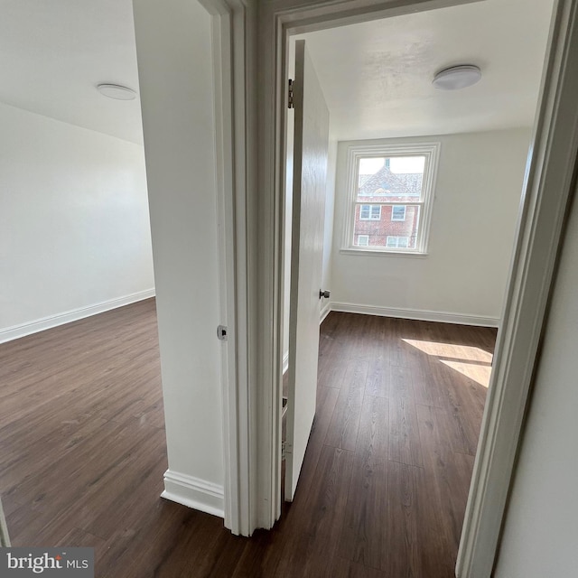 hall featuring dark wood-type flooring and baseboards