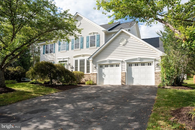 view of front of house featuring aphalt driveway, an attached garage, and a shingled roof