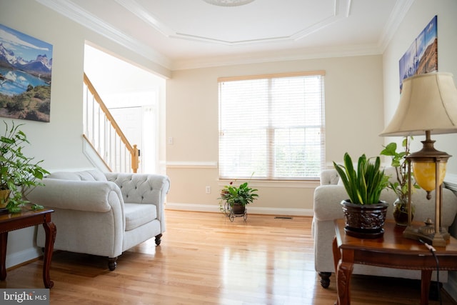 sitting room with stairway, light wood-type flooring, baseboards, and ornamental molding