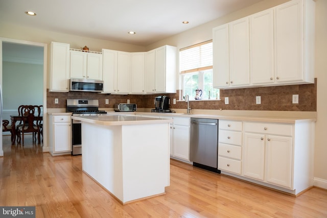 kitchen featuring light wood-style flooring, backsplash, white cabinetry, appliances with stainless steel finishes, and light countertops