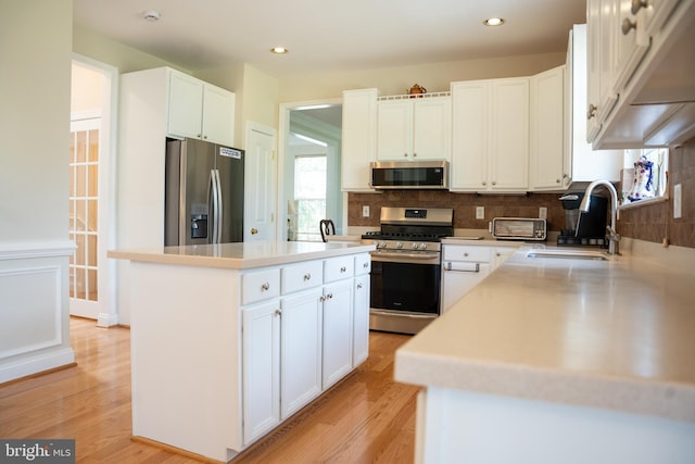 kitchen with backsplash, stainless steel appliances, light countertops, and light wood-style floors