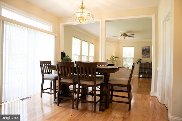 dining space featuring ceiling fan with notable chandelier, visible vents, light wood-type flooring, and ornamental molding